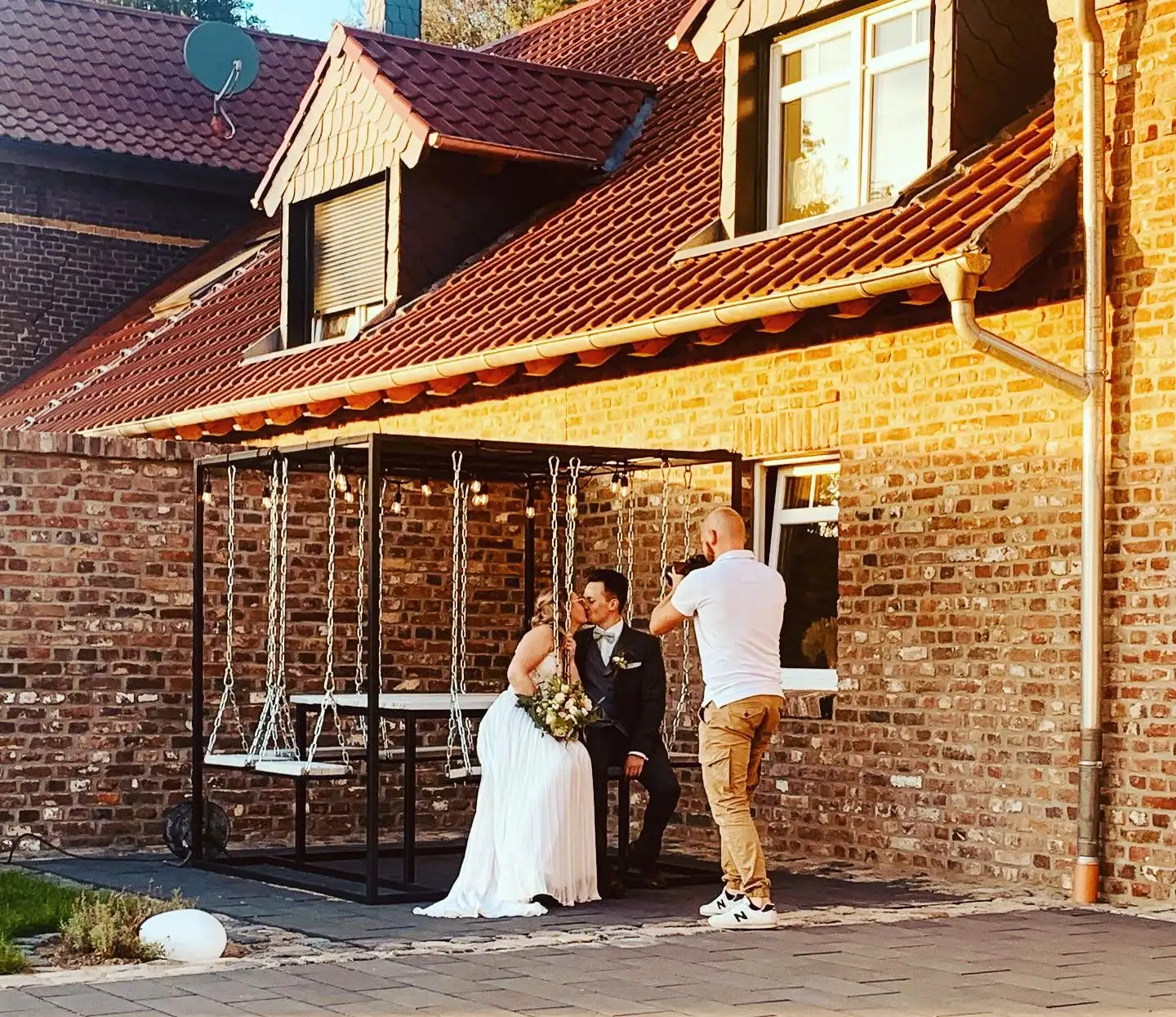 Brautpaar auf der Schaukel vor der Backsteinwand des Hofes